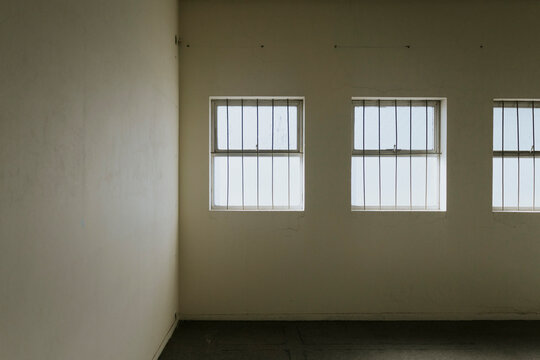 Interior of a dimly lit room featuring barred windows