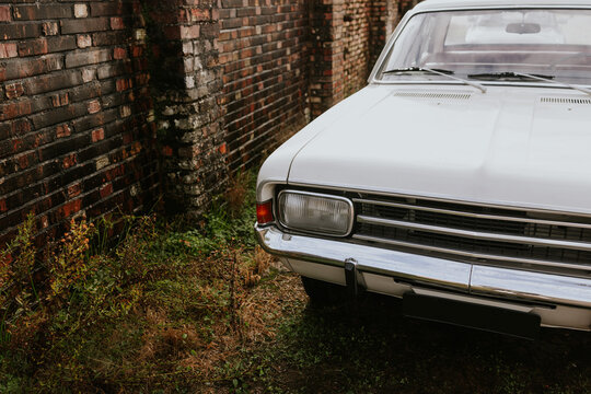 Classic white car beside aged brick wall