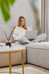Freelance student working from home on study tasks while sitting on couch in cozy living room setting