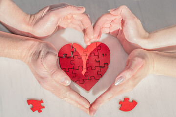 Valentine's Day social media concept of love, care, protection, and preservation. A red puzzle heart is surrounded by supportive gestures of caring from female and male hands.