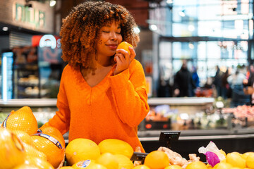 Young woman enjoying the fresh scent of citrus fruit while grocery shopping