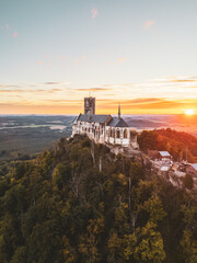 Bezdez Castle stands majestically on a hilltop, its medieval ruins bathed in warm sunset light. Surrounded by lush greenery, it offers a breathtaking view of the Czech landscape during dusk.