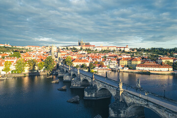 The beauty of Prague Castle and Charles Bridge at dawn. The sun rises over the Vltava River, illuminating the historic buildings and creating a serene atmosphere.