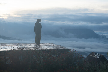 Obraz premium Silhouette of a traveler standing quietly on a wooden platform at sunrise