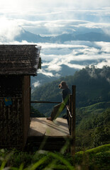 Naklejka premium Silhouette of a person resting on a wooden balcony overlooking misty mountains