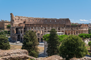 Obraz premium Italy - Rome - Colosseum - Exterior view with the surrounding green landscape, trees, and the ancient Roman amphitheater structure.