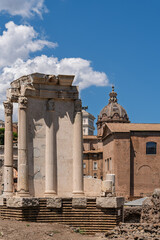 Obraz premium Italy - Rome - Temple of Vesta - Ancient circular temple with columns, a podium, and a church dome in the Roman Forum archaeological site.