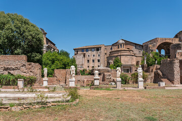 Italy - Rome - House of Vestal Virgins - Ancient marble statues with a church and ruins in the Roman Forum archaeological courtyard.