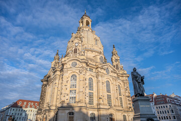 Frauenkirche stands tall in Dresden, Germany. Visitors admire the church structure and dome under a clear sky. The atmosphere is festive with decorations for Christmas.