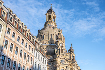 Frauenkirche in Dresden showcases its large dome against a blue sky. The church is surrounded by historic buildings, creating an interesting view. Many visitors enjoy the scenery.