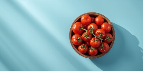 Arrangement of cherry tomatoes in a bowl seen from above against a blue backdrop, ideal for recipe or produce display