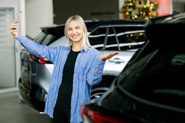 Customer taking selfie with new car in dealership