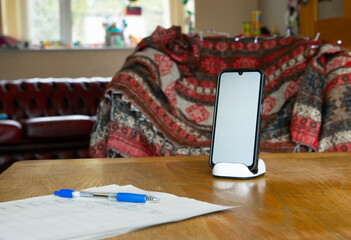 Home office with mobile phone with blank space on stand on wooden table 