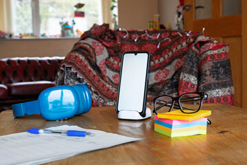 Home office with mobile phone with blank space on stand on wooden table 
