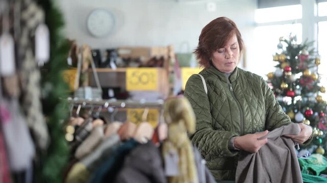 Woman picks up clothes and choose trousers. Changing wardrobe, shaping style of clothing, filling wardrobe with modern stylish clothes. Chain store of affordable clothing, New Year Eve sale