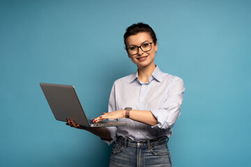 Smart happy IT woman holding using on laptop pc computer chatting online isolated on blue background