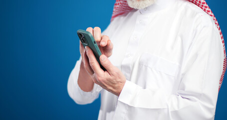 Senior man holding mobile phone using mobile app, text message on blue background selective focus