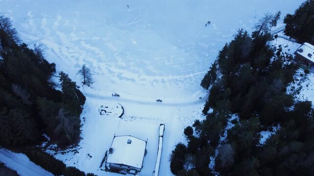 Top-down aerial drone footage of a frozen lake in Champex, Switzerland, with people ice skating in winter. Shot in 4K by a professional drone pilot using a DJI Mini 2.