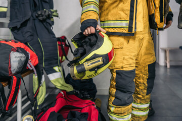 Firefighter holding helmet in fire station locker room