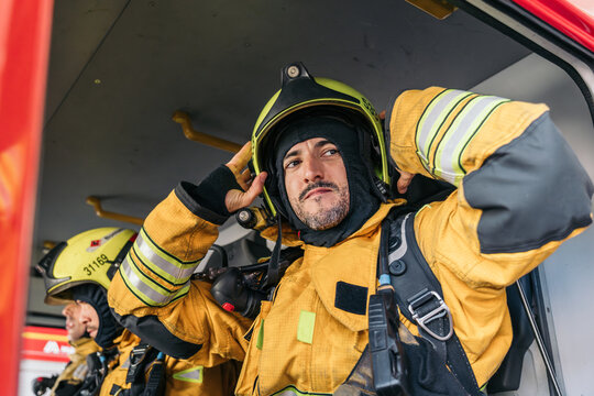 Firefighter wearing helmet inside firetruck getting ready for action