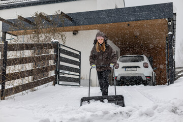 Shoveling snow from a driveway after a heavy snowfall, woman with a snow shovel