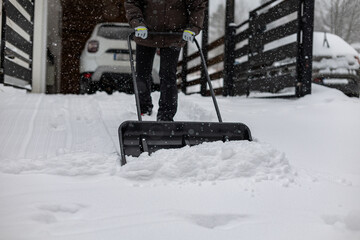 Close-up of a large snowplow-style shovel being used to clear snow from a driveway
