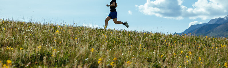 Woman runner running on the beautiful flowering grassland mountain top