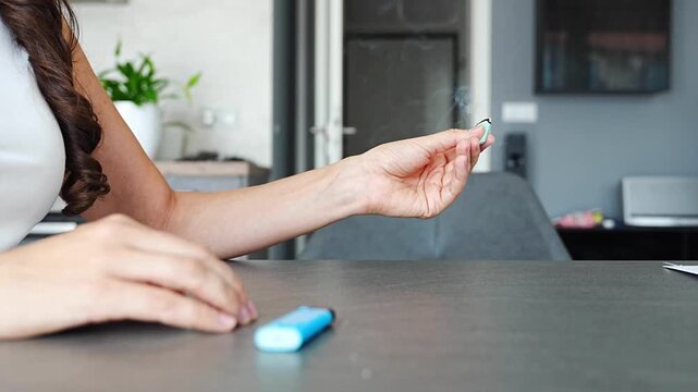 Close up of woman hands burning aromatic tablet and spreading smoke in home office. Aromatherapy ritual, relaxation process and mindful pause within everyday work routine in real life workspace