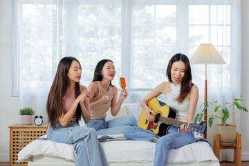 Friends singing and playing guitar together in a bedroom.