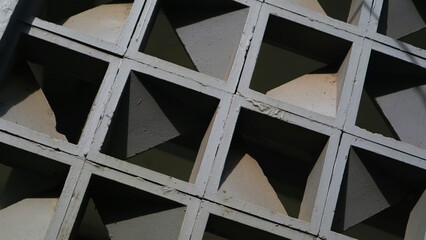 Close-up view of a metal grate with triangular openings in a dark setting. Geometric pattern...