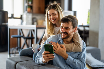 Smiling couple embracing while looking at smartphone. People sharing social media on cellphone.