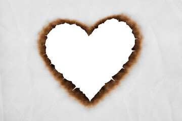 heart shaped transparent burned hole in white paper with dark charred edges creating a romantic and dramatic background for design and love themed concepts