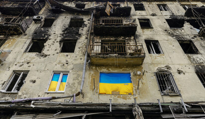 national flag of Ukraine on the wall of a house destroyed during the war in an empty city