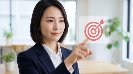 Confident Asian businesswoman pointing at virtual dart target icon with arrow, symbolizing focus, goal achievement, accuracy, strategy, leadership and successful decision making.