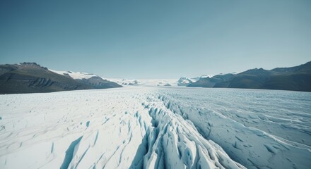 Vast glacial landscape with jagged ice formations and snow-capped mountains under a clear blue sky.
