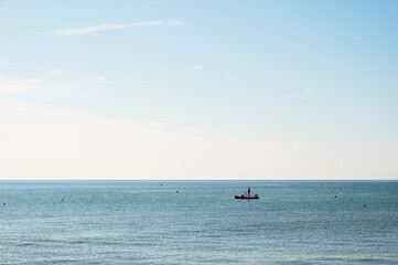 Fototapeta premium people silhouette on a boat in front of a Adriatic Sea beach during a summer day, Bibione Pineda, Venice, Italy