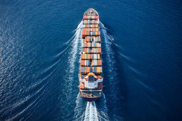 Aerial top-down view of a massive cargo ship sailing steadily through calm, deep blue ocean waters