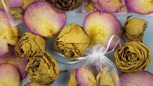 Organza sachets filled with dry rose petals, dried rose buds lie on a table, top view