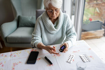 Senior Woman Checking Her Blood Sugar Levels by Glucose Meter at Home
