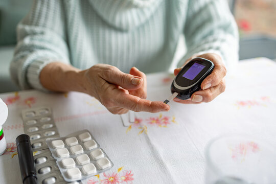 Senior Woman Checking Her Blood Sugar Levels by Glucose Meter at Home
