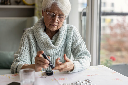 Senior Woman Checking Her Blood Sugar Levels by Glucose Meter at Home
