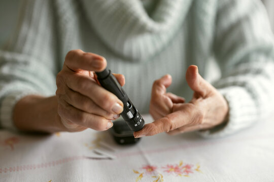 Senior Woman Checking Her Blood Sugar Levels by Glucose Meter at Home
