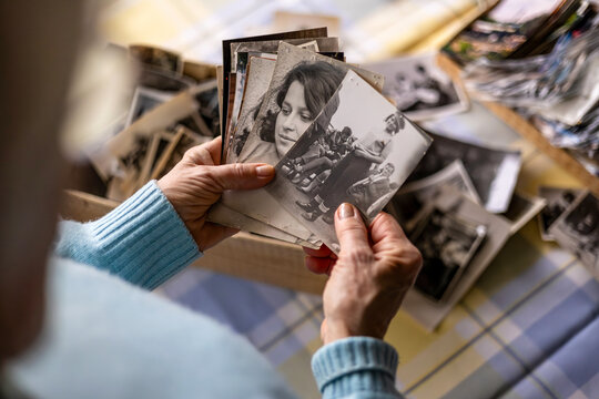 Senior woman looking at old photographs and reminiscing

