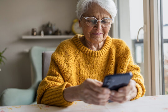 Senior woman using smart phone at home
