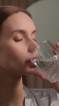 Healthy woman drinking water glass in bathroom morning routine refreshing face hydration wellness lifestyle Caucasian female girl at home skincare balance nutrition aqua health habit freshness beauty