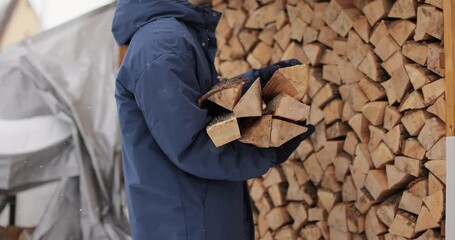 Man takes logs from a woodcutter in his hands for heating in the house.