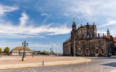 Sunlit Theaterplatz square with the magnificent baroque cathedral and historic guard house. Wide angle view of European city architecture under a bright blue sky with wispy white clouds