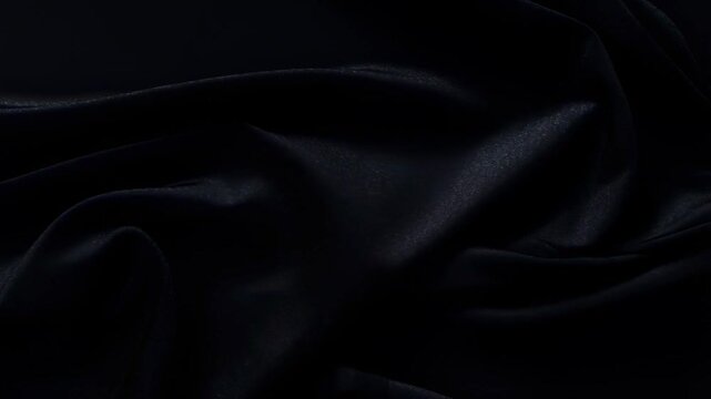 Flowing black fabric waves in smooth continuous motion elegantly unfolding in dark ambiance