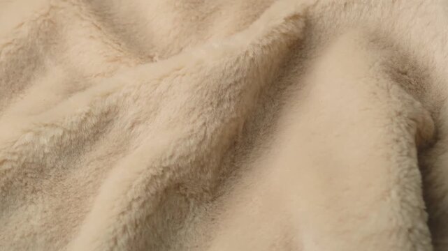 Detailed view of soft luxurious light beige fluffy fabric showing natural texture and warmth