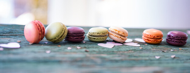 Colorful macarons arranged in a row on a old wooden table.